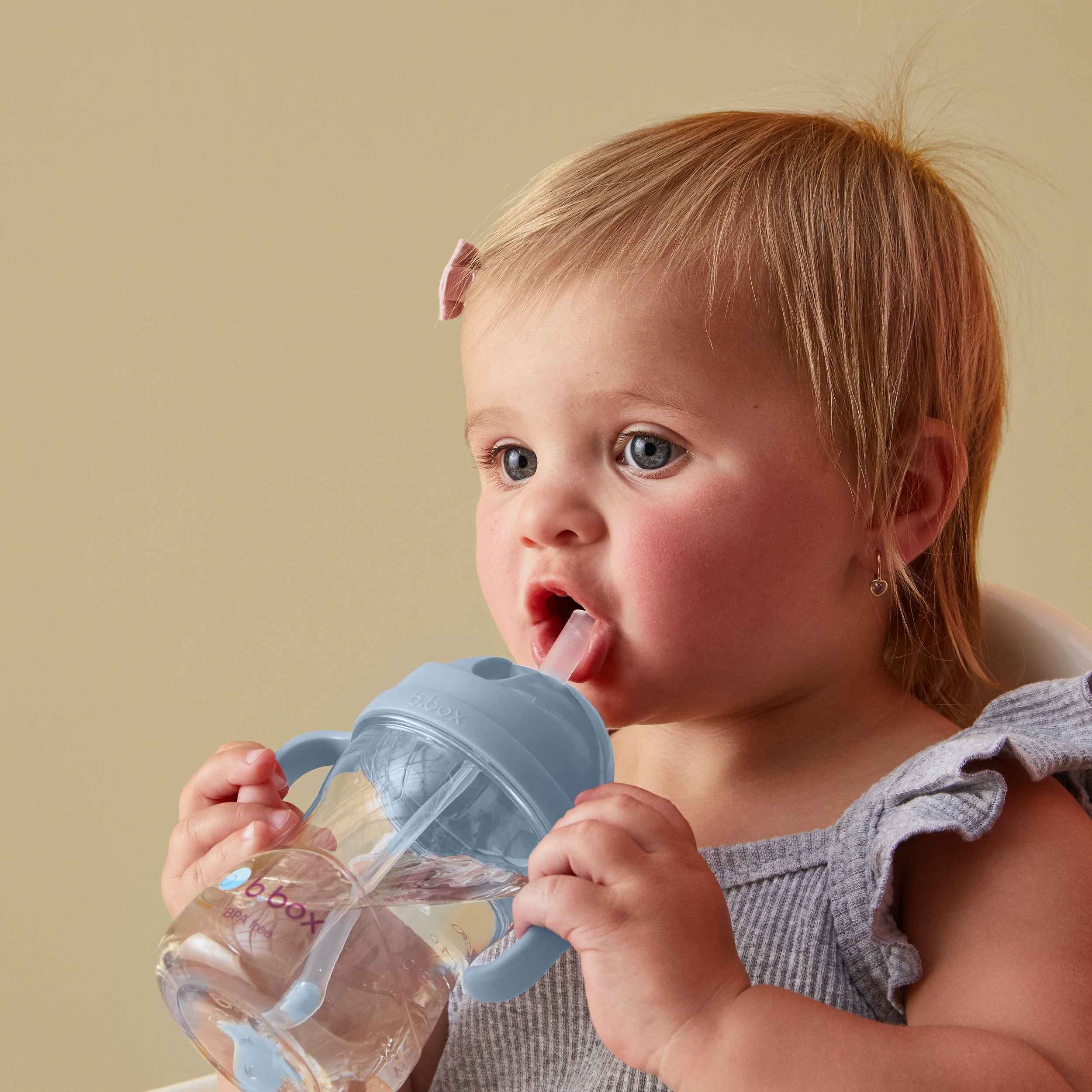 Baby drinking independently from a b.box sippy cup with weighted straw, ocean colorway
