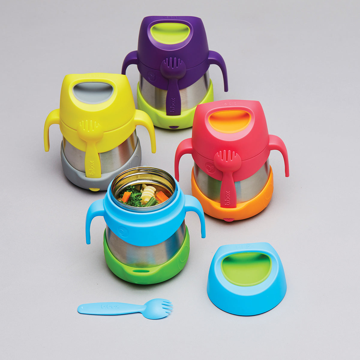 Range of b.box insulated food jars in bright colorways with stainless steel bodies, easy-grip handles and included forks, one open showing warm vegetables inside