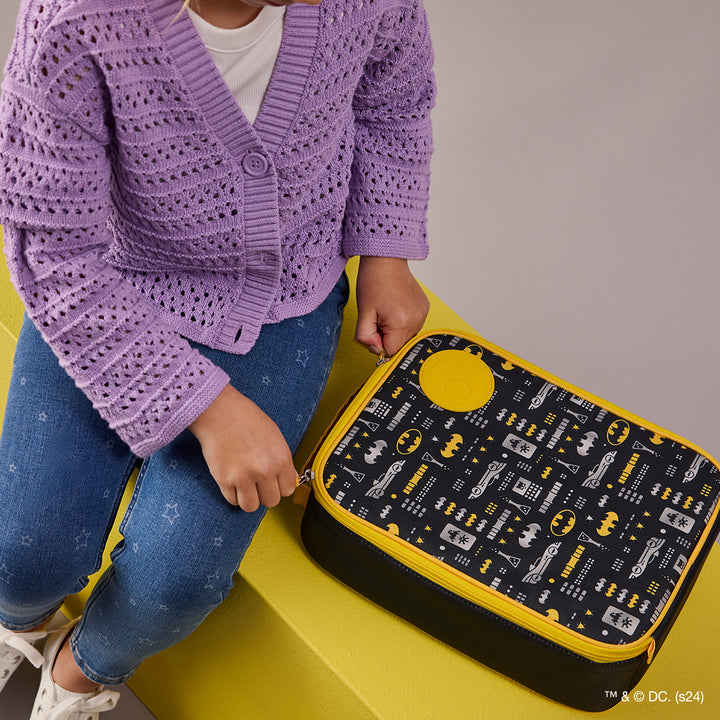 Insulated lunch bag with a Batman theme, featuring various Batman logos and a yellow zipper and handle