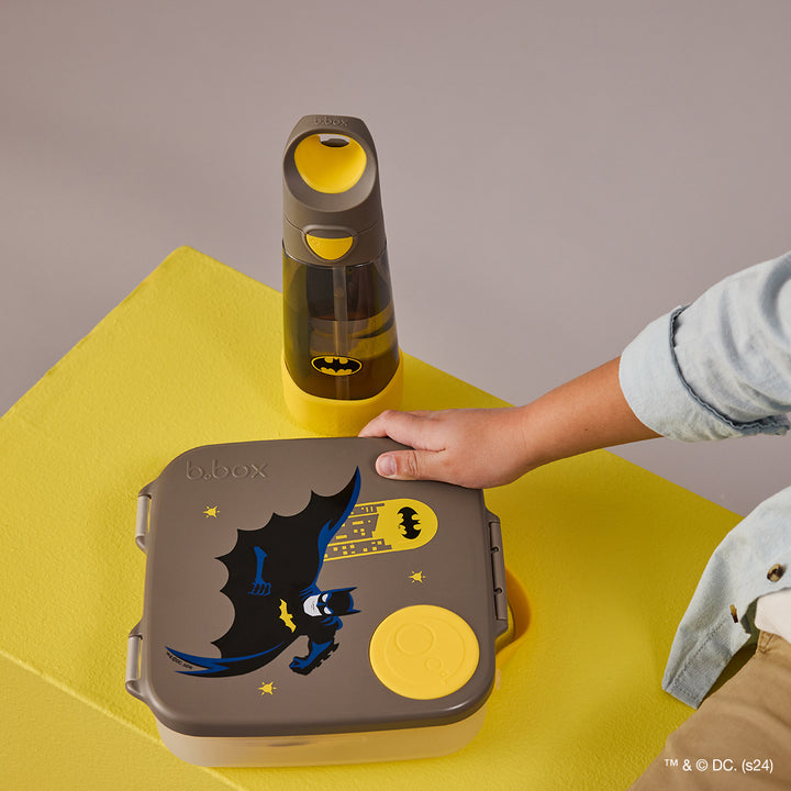 A Batman-themed kids lunchbox with a depiction of the character in his iconic costume against a gray background with yellow accents.