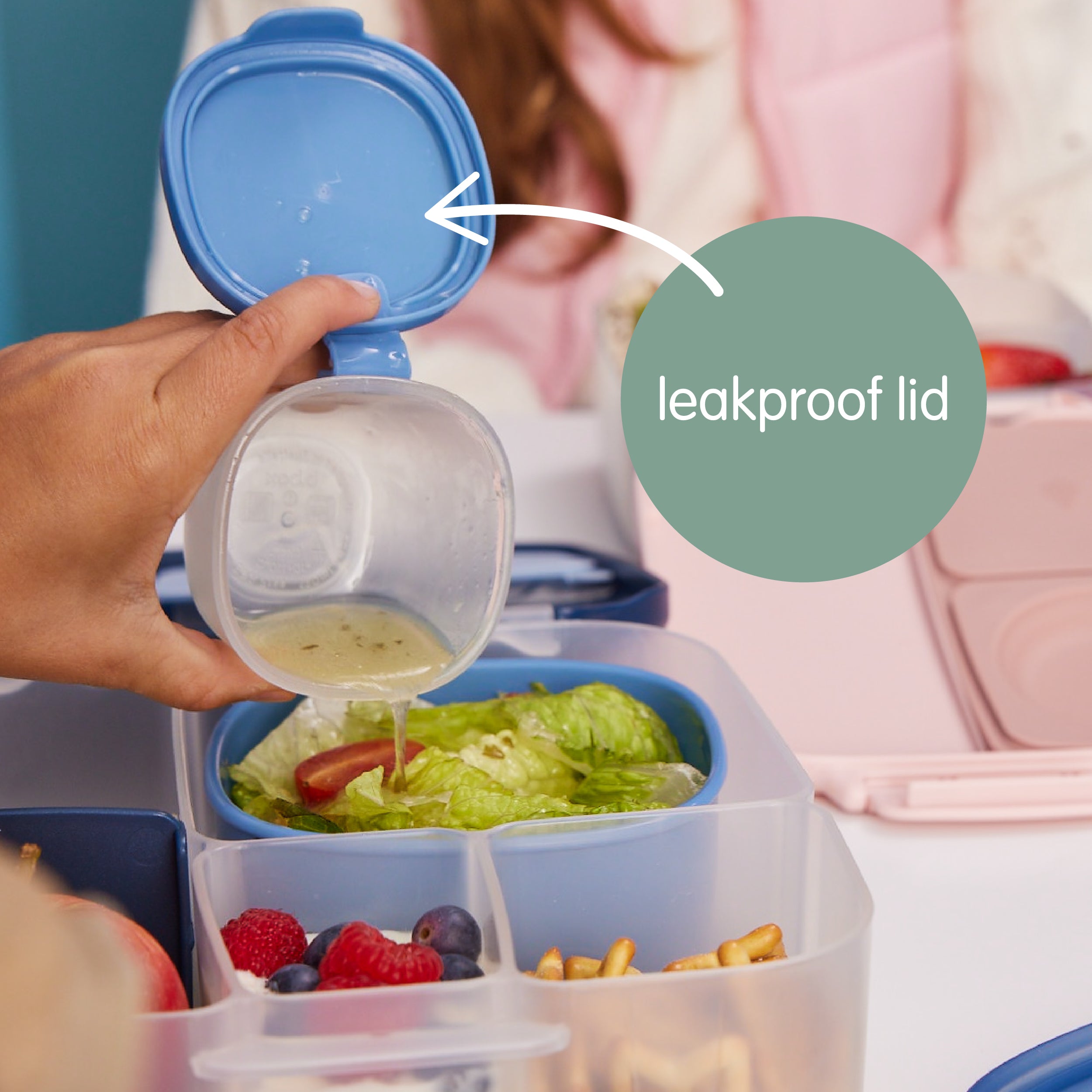 Set of three white snack containers for kids with pink lids stacked on a white background