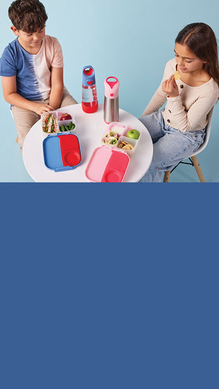 two kids sitting at table eating lunch