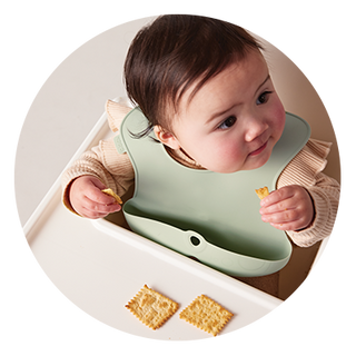 baby eating crackers with silicon bib on
