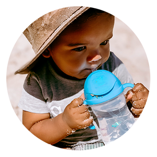 little boy drinking from sippy cup at the beach